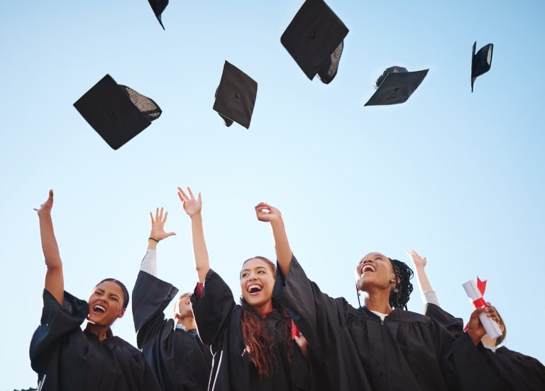 Happy students throwing their graduation caps in the air